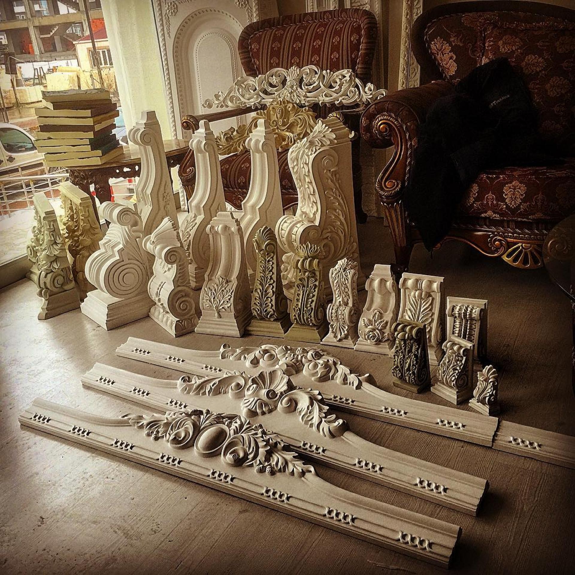 Console și frontoane decorative din poliuretan alb pe pardoseală din lemn într-o expoziție de interior.