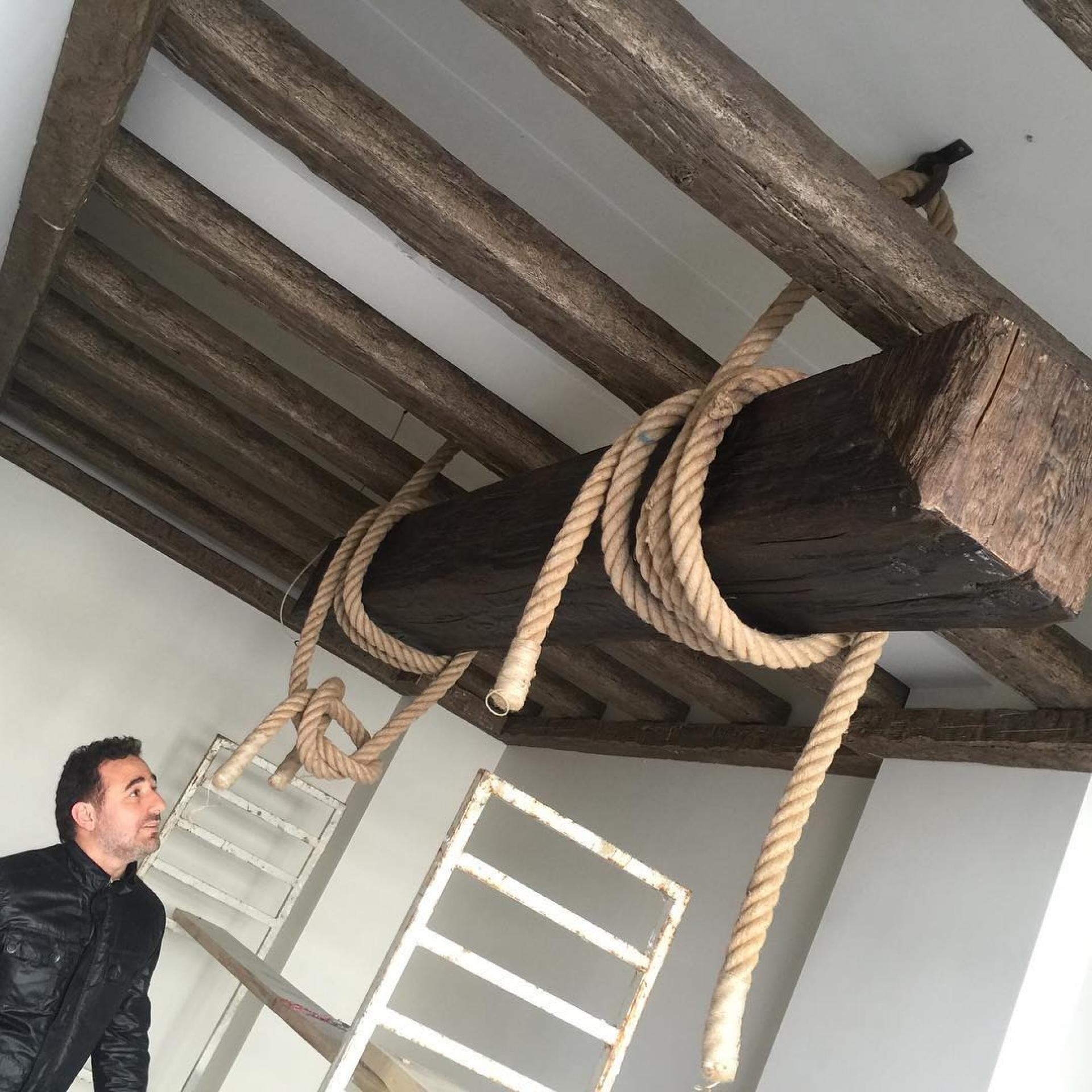 Grindă decorativă din poliuretan ancorată cu frânghii pe un plafon cu căpriori din lemn masiv imitat.
