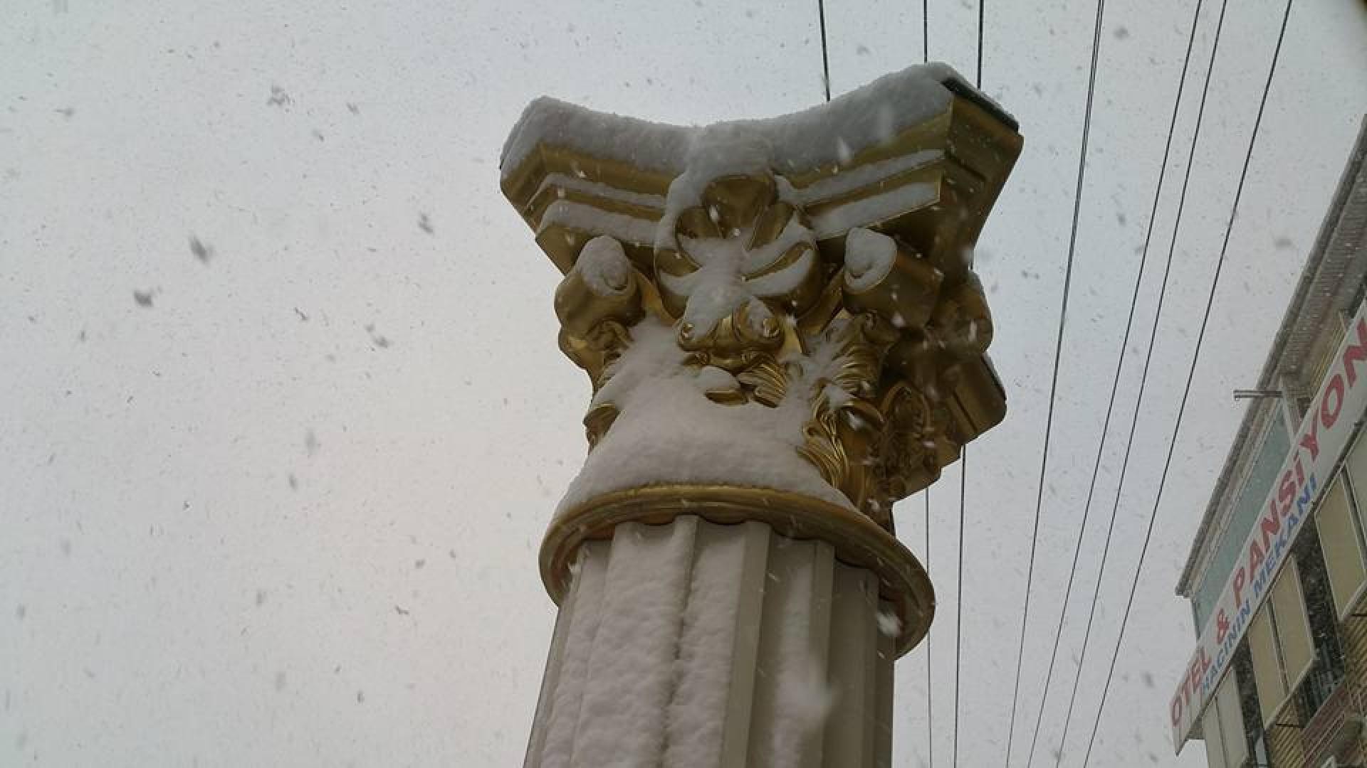 Capitel de coloană din poliuretan decorativ cu detalii aurii acoperit de zăpadă pe o fațadă exterioară.