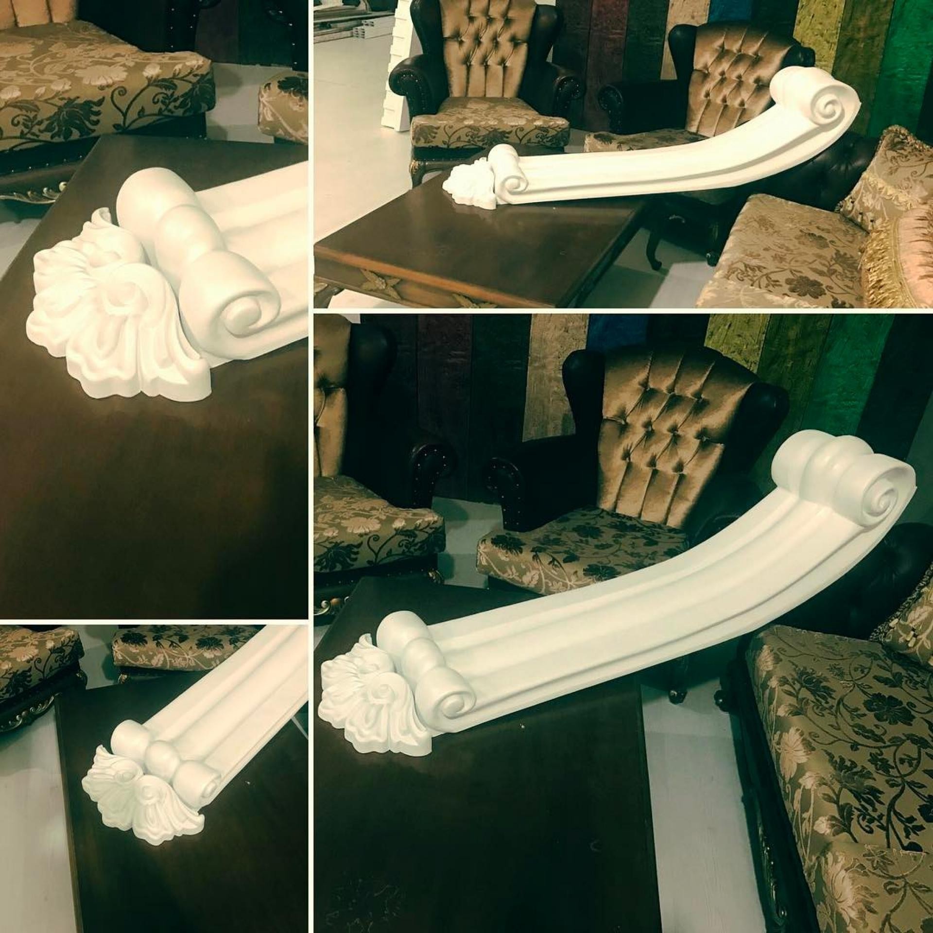 Consola decorativa din poliuretan alb P99143 cu profil curbat si ornamente sculptate expusa pe o masa din lemn
