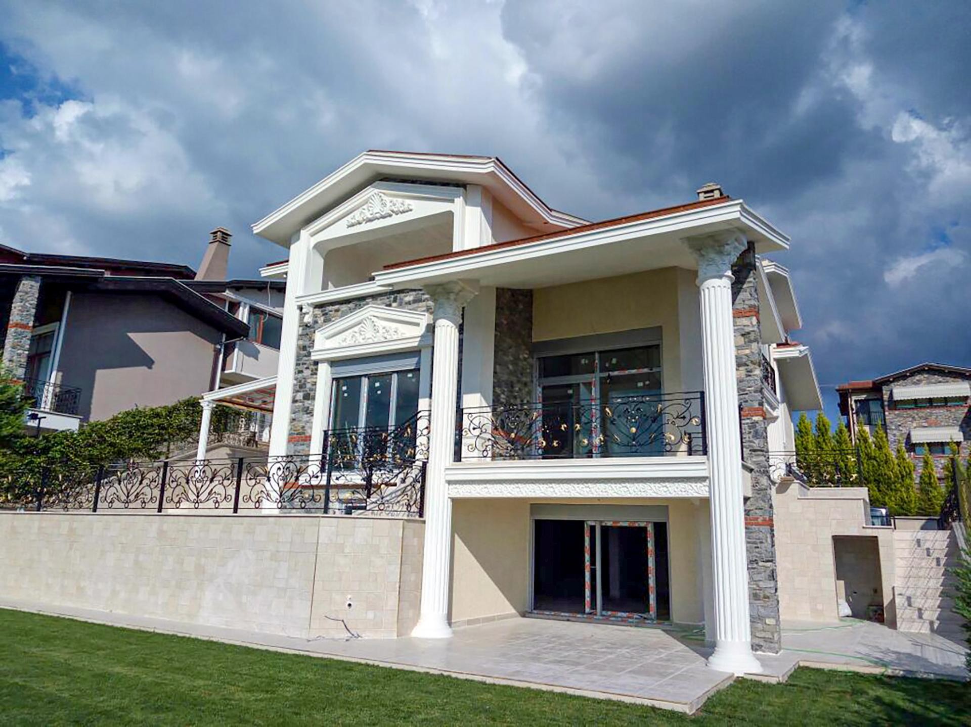 Fațadă exterioară de vilă clasică decorată cu coloane canelate din poliuretan, ancadramente de fereastră și frontoane decorative.