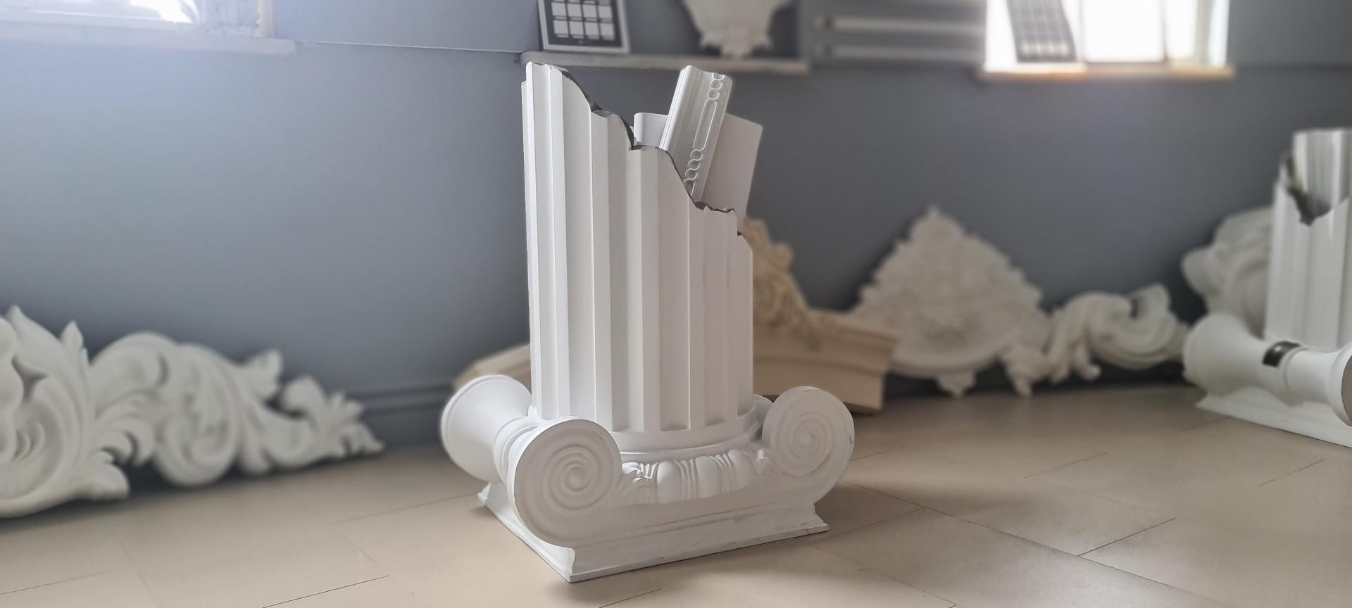 Sectiune coloană ionică din poliuretan alb P5240I și trunchi canelat P5840 pe fundal gri într-un atelier de design interior.