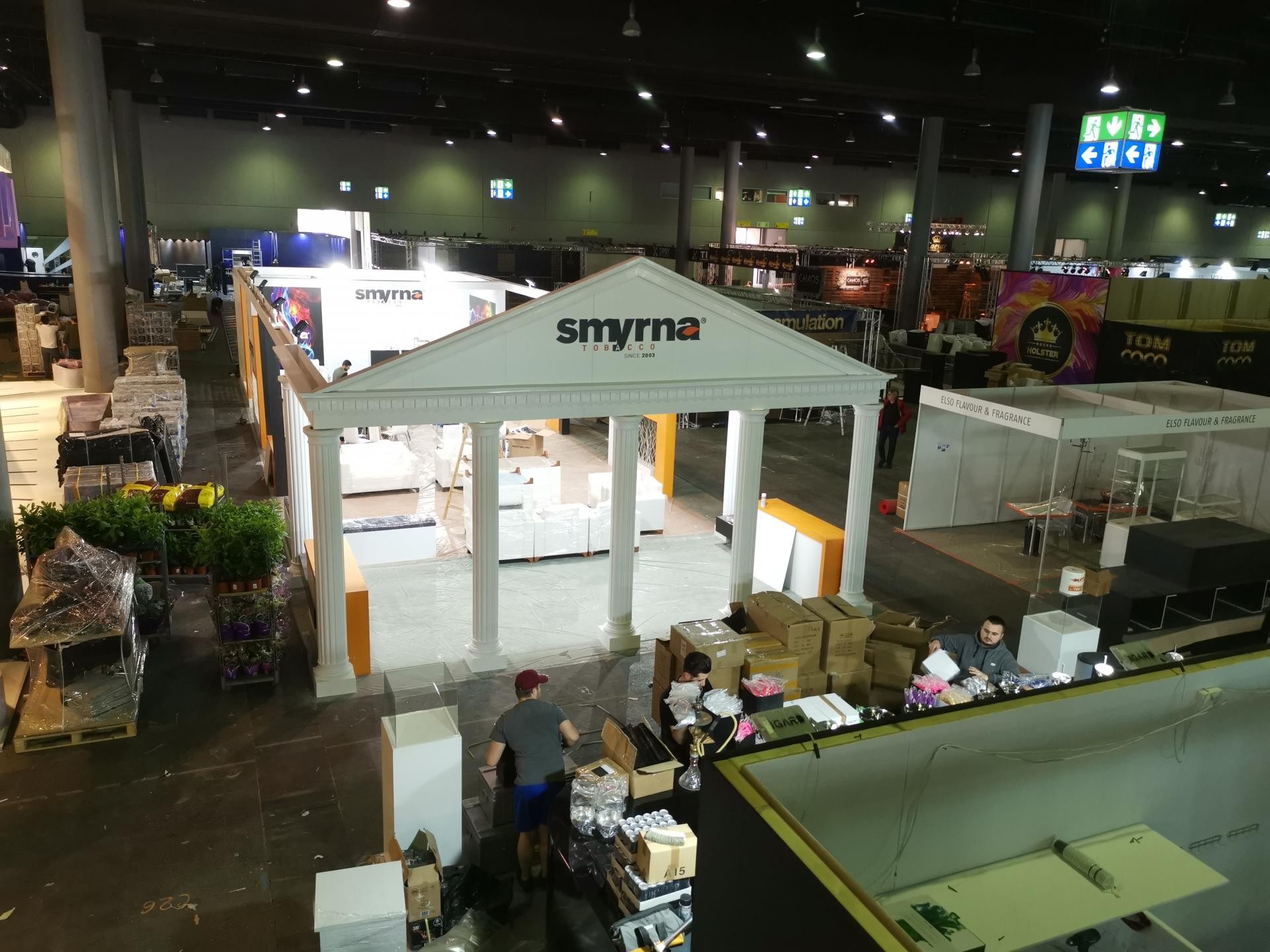 Stand expozițional cu coloane canelate și ancadramente din poliuretan alb pe un fundal industrial.