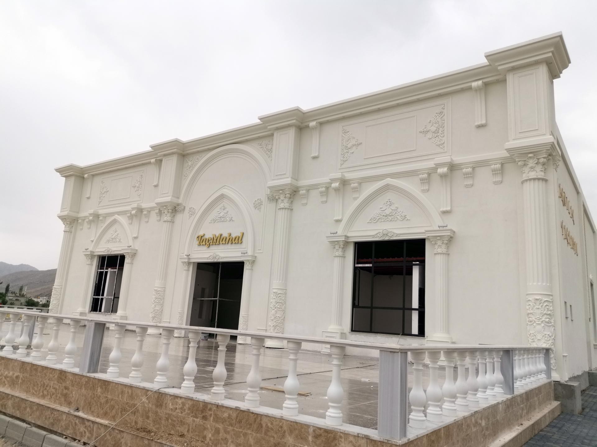 Fațadă albă din poliuretan cu pilastri, ancadramente decorative și arcade simetrice în stil neoclasic.