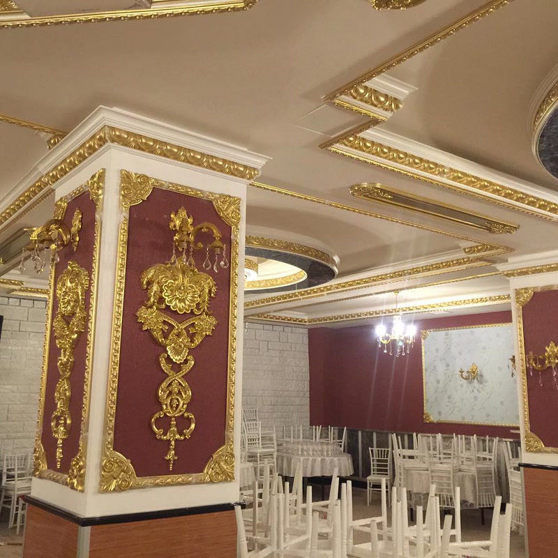 Stâlp decorat cu panouri vișinii, profile din poliuretan aurit și aplicații ornamentale clasice în sală de festivități.