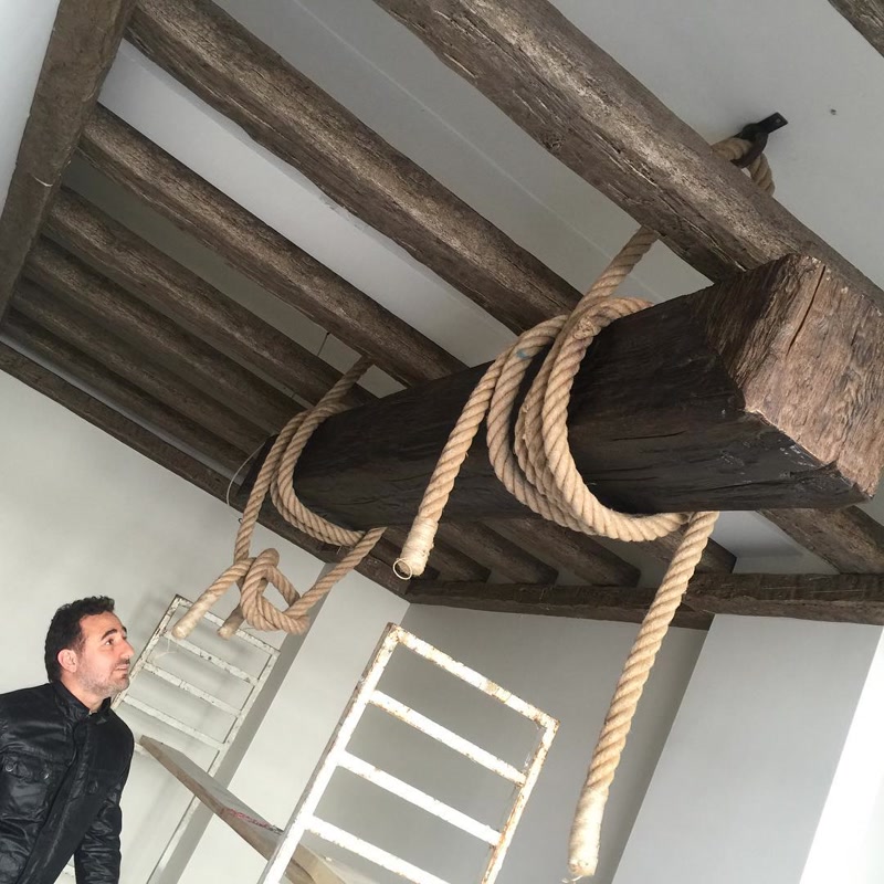 Grindă decorativă din poliuretan ancorată cu frânghii pe un plafon cu căpriori din lemn masiv imitat.