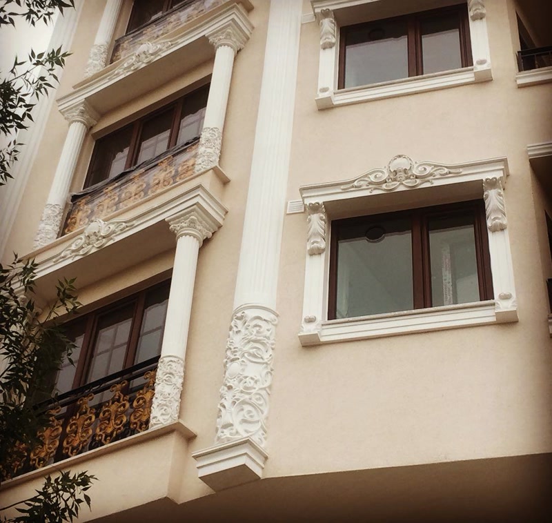 Fatada cladirii decorata cu coloane din poliuretan P5420, ancadramente P1456 si frontoane profilate P2839 pe fond crema.