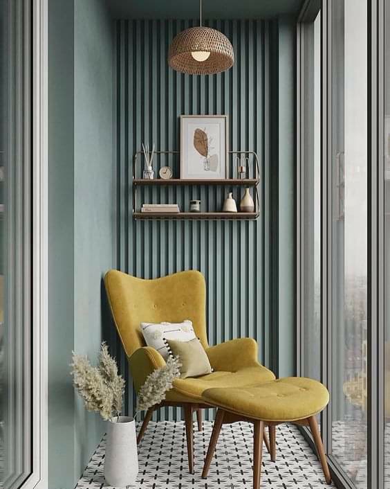 Perete decorat cu panouri verticale din poliuretan verde salvie si un fotoliu galben intr-un balcon modern.