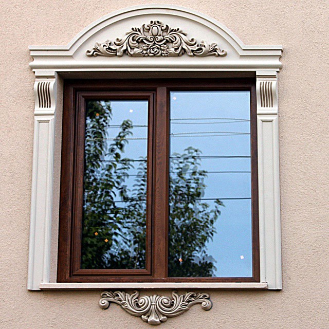 Ancadramente albe din poliuretan cu fronton decorativ clasic și pilatri pe o fațadă cu tencuială bej.