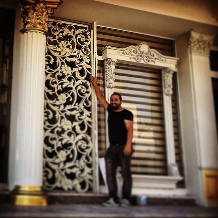 Fațadă clasică decorată cu panou traforat din poliuretan, coronament de fereastră și coloană ornamentată.