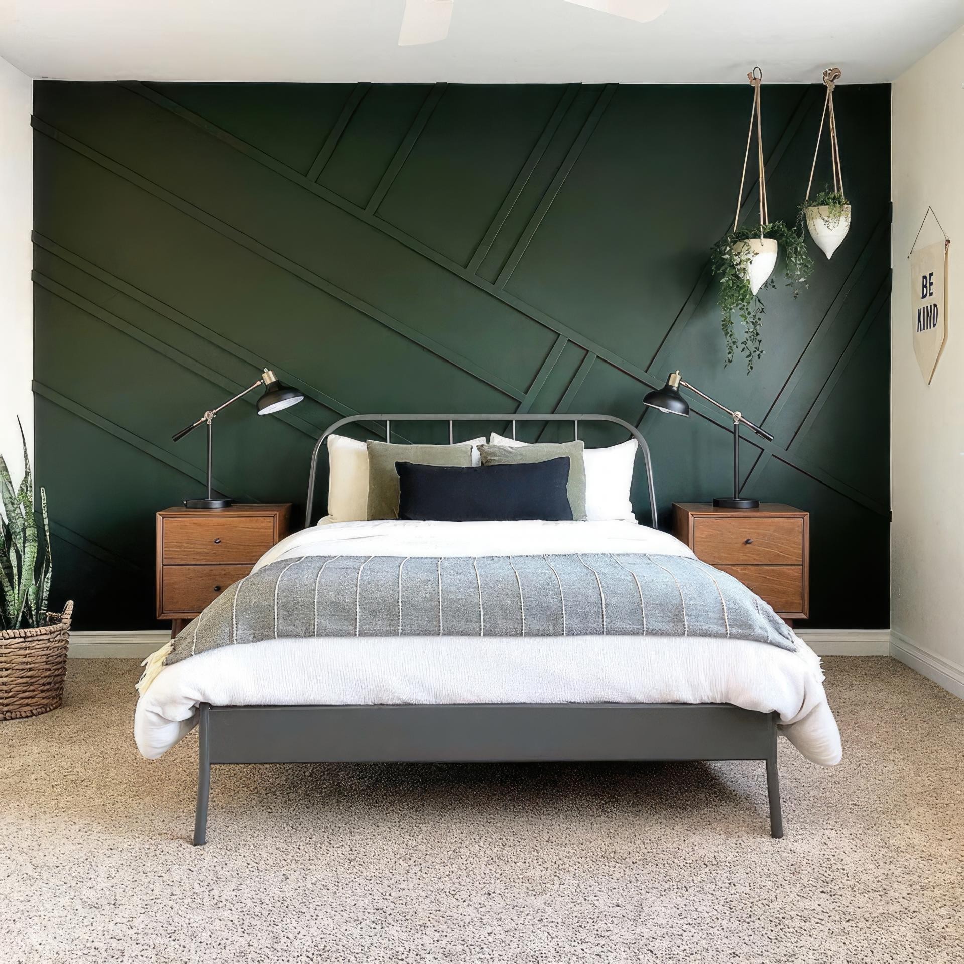Dormitor modern cu perete verde închis decorat cu profile poliuretanice geometrice, noptiere din lemn și lămpi metalice.
