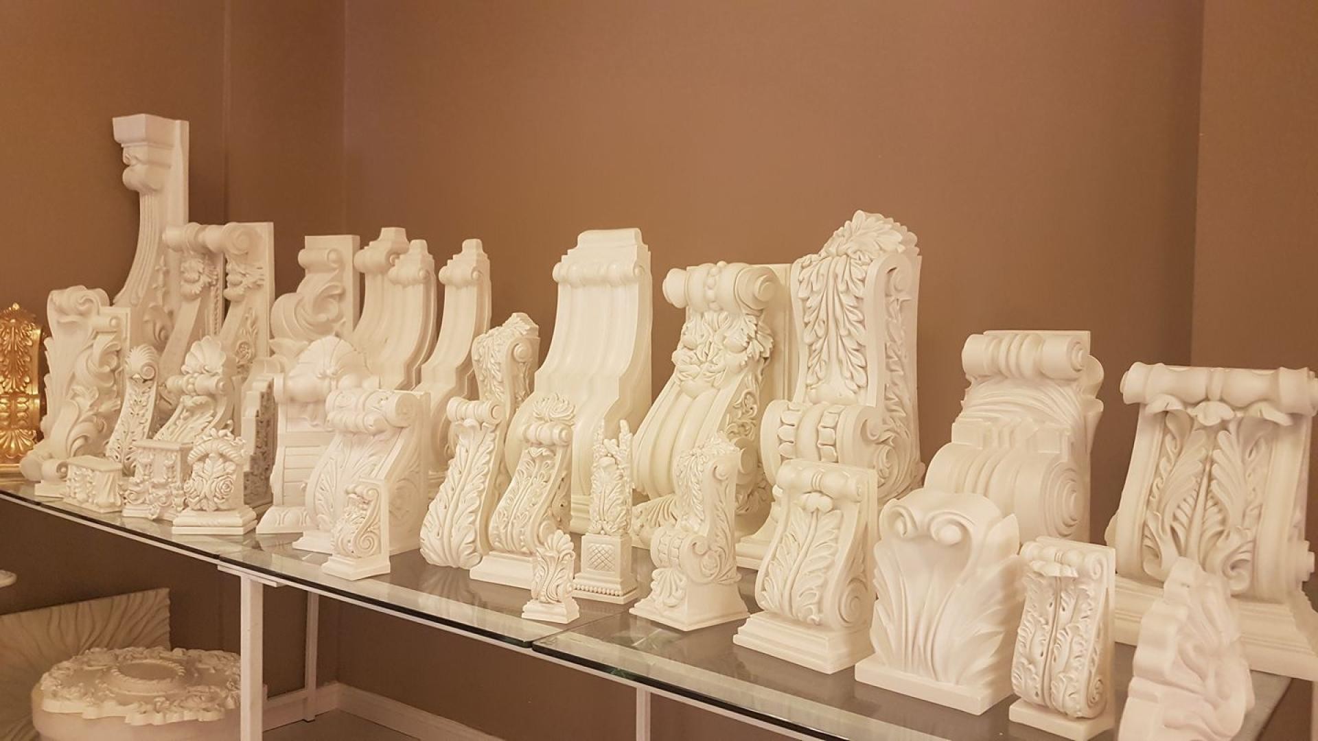 Diverse modele de console din poliuretan alb pe rafturi de sticlă pentru decorațiuni exterioare și interioare.