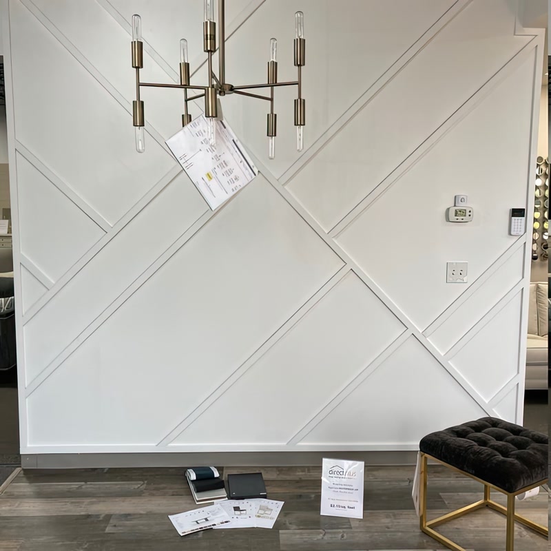 Perete alb decorat cu profile din poliuretan în modele geometrice diagonale și lustre din alamă