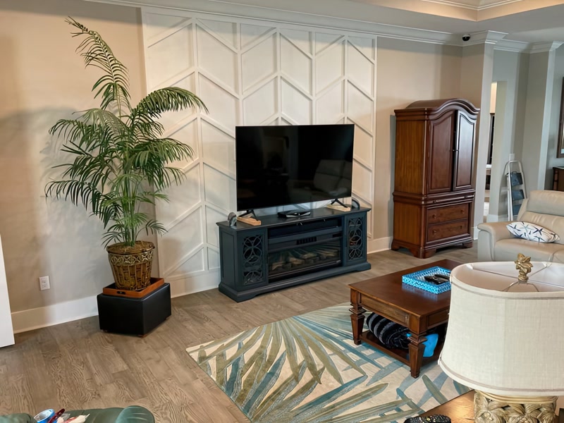 Perete TV decorat cu profile din poliuretan în model chevron alb pe fundal bej într-un living modern