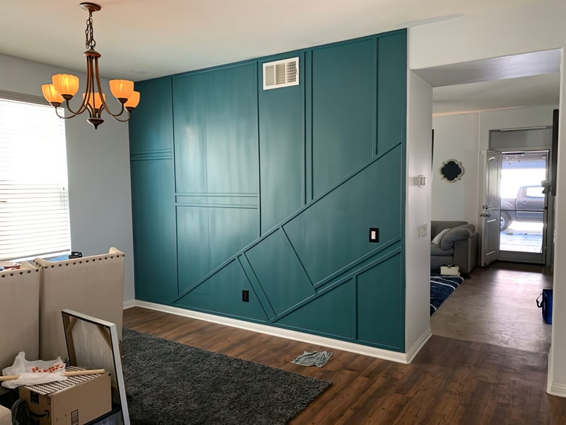 Perete accent verde-albăstrui decorat cu profil din poliuretan în linii geometrice diagonale și drepte într-un salon modern.