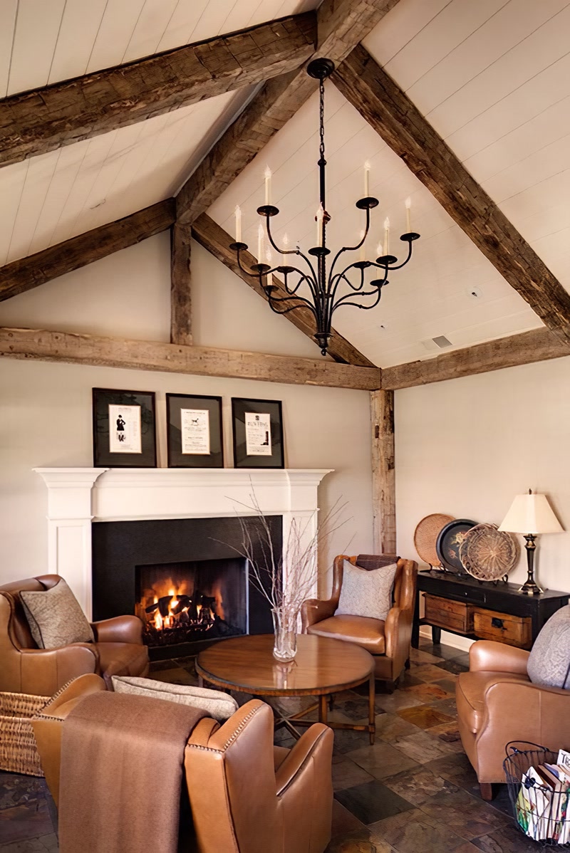 Plafon înalt cu grinzi decorative din Poliuretan P1981, șemineu alb și fotolii din piele în salon rustic.