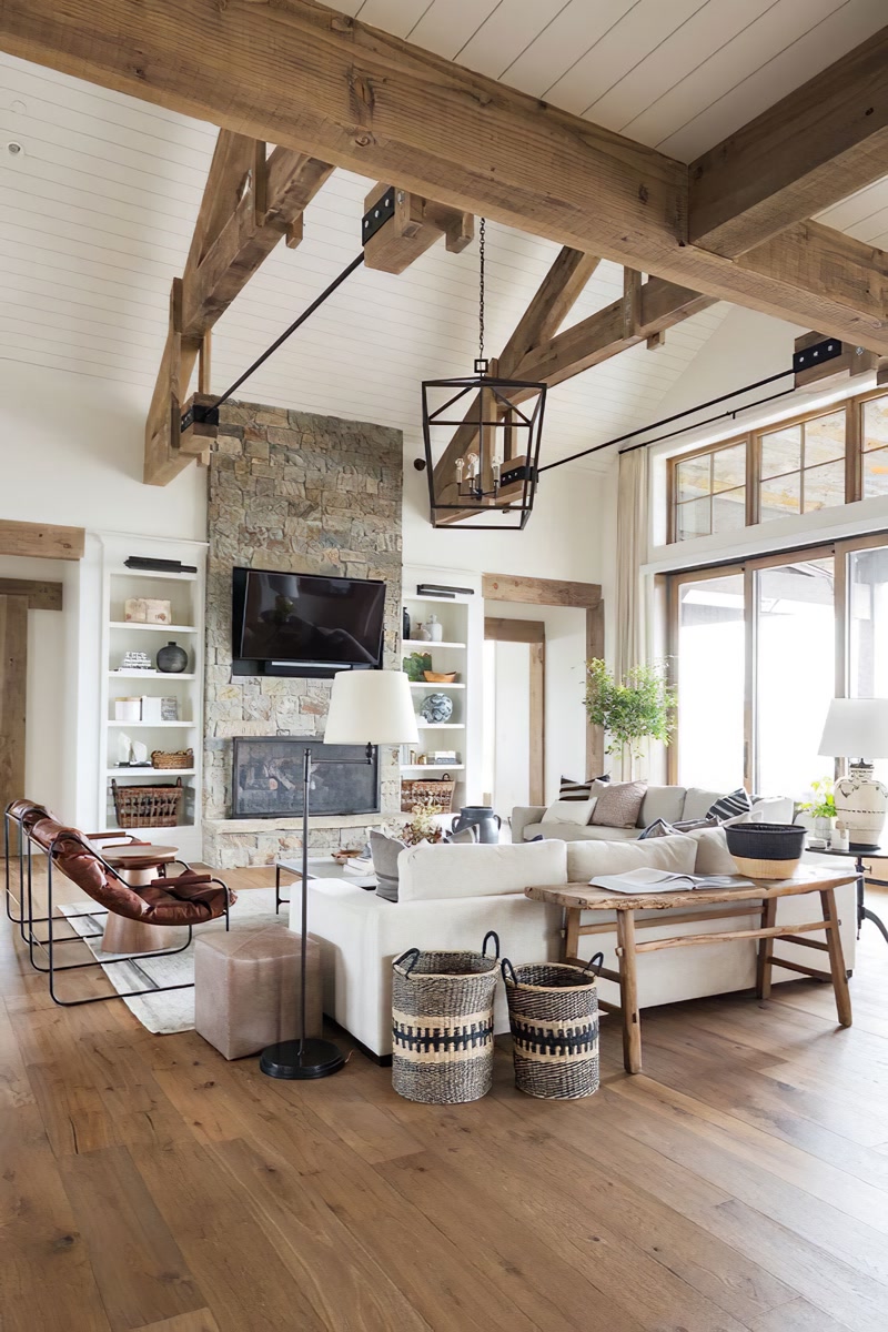 Tavan înalt amenajat cu grinzi decorative din poliuretan, șemineu din piatră și mobilier rustic în living luminos.