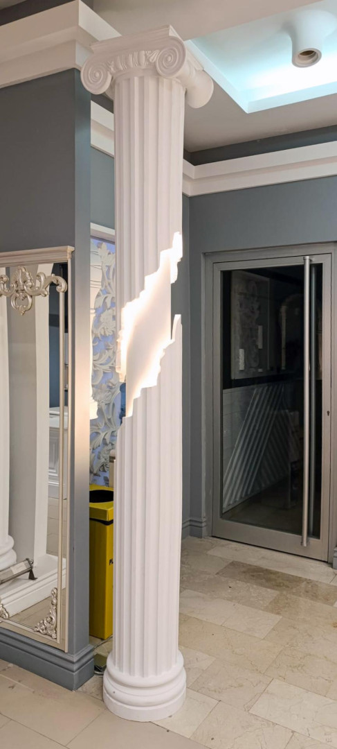 Coloană din poliuretan albă cu capitel ionic și secțiune iluminată cu LED integrat într-un interior modern.