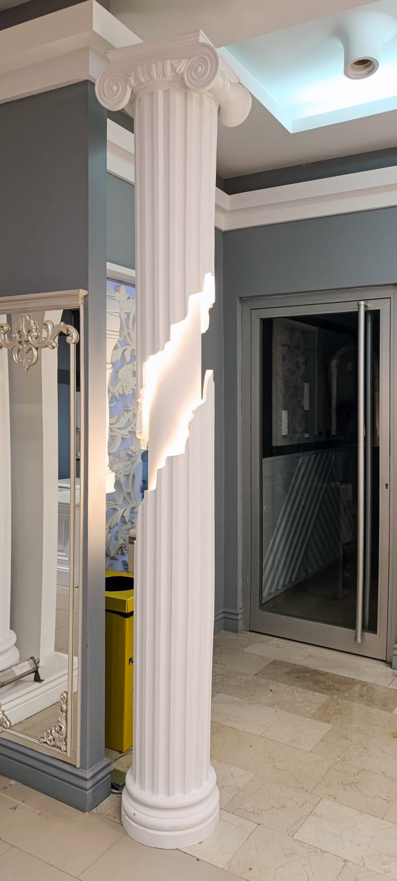 Coloană din poliuretan albă cu capitel ionic și secțiune iluminată cu LED integrat într-un interior modern.