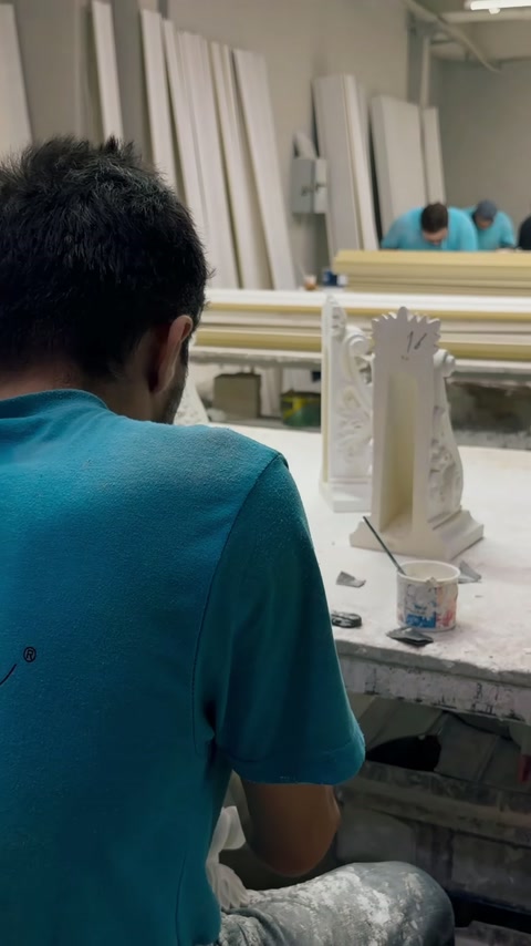 Un operator finisează un pilastru decorativ la masa din atelier.