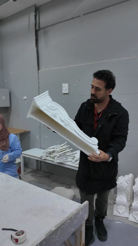 Bărbat ține o piesă decorativă lângă masa de producție
