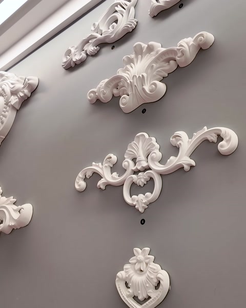 Ornamente și console decorative montate pe un perete gri