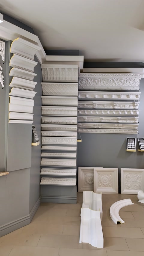 Mostre de cornișe și profile decorative organizate pe peretele showroomului