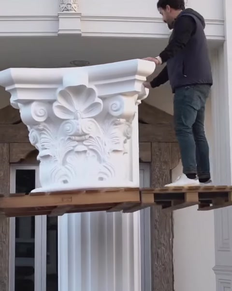 Muncitor pe schelă ridică o piesă de capitel corintic