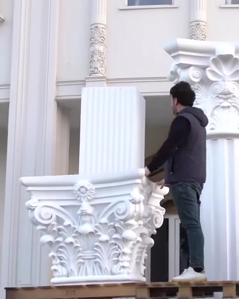 Muncitor pe schelă lângă capitel corintic, doi stâlpi vizibili