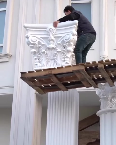Muncitor pe schelă montează capitelul unui stâlp nou