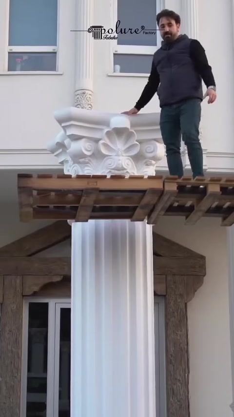 Montatorul coboară atent capitelul peste partea superioară a coloanei