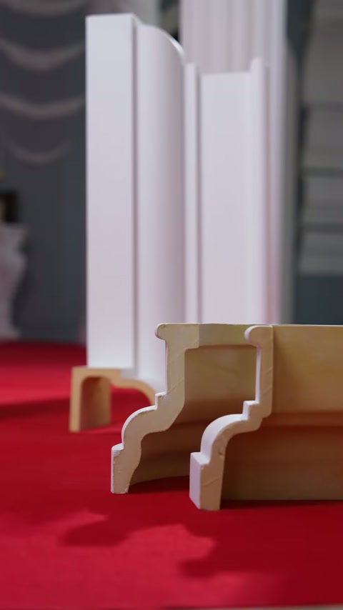 Videoclipul arată mostre secționate de profile ornamentale pe masa din showroom.