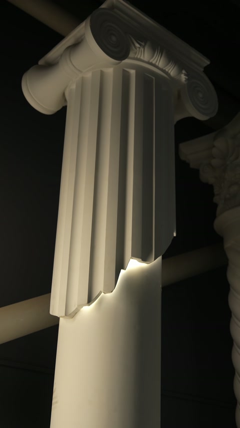 Capitel ionic și caneluri verticale evidențiate de iluminarea decorativă