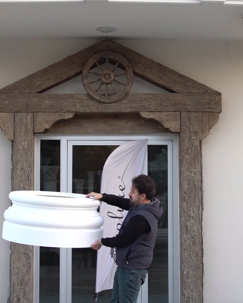 Cornișă decorativă albă este manipulată pentru montaj