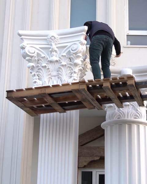 Montatorul lucrează la fixarea capitelului pe fațadă