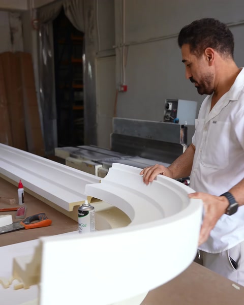 Lucrătorul ajustează un profil decorativ curbat de dimensiuni mari