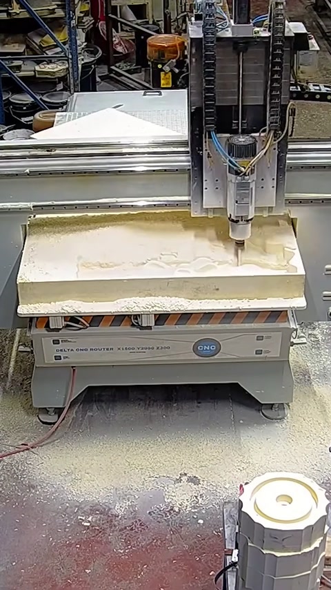 Mașina CNC sculptează relieful decorativ într-un panou din atelier.