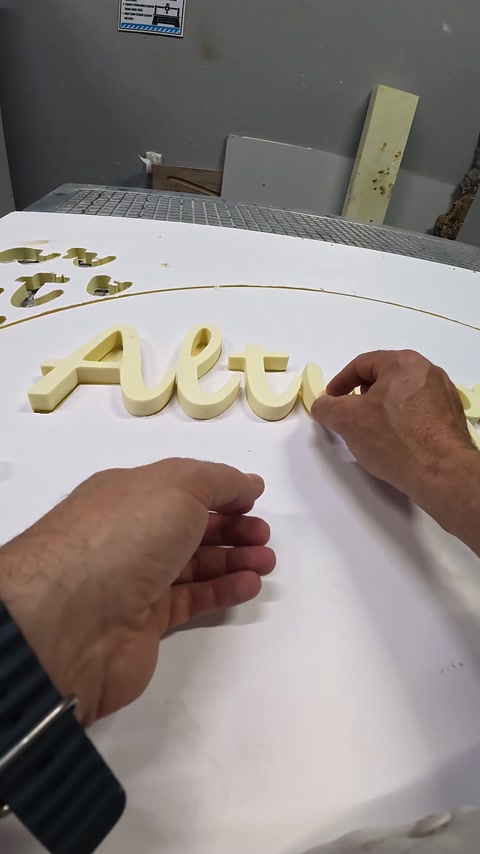 Literele decorative sunt poziționate manual pe suprafața albă a panoului.