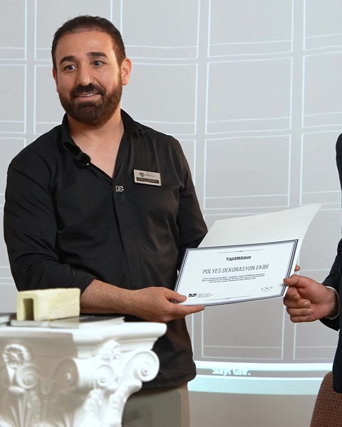 Un reprezentant prezintă un certificat lângă un element ornamental decorativ.