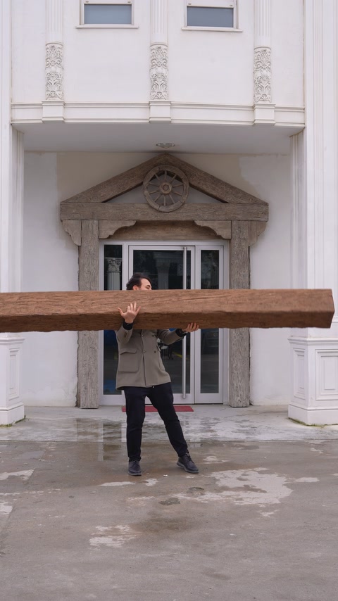 Operatorul ține deasupra capului grinda ușoară cu aspect de lemn.