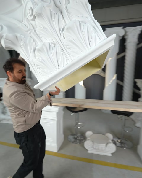 Muncitor transportă capitelul sculptat spre rândul de coloane finisate.