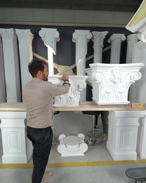 Rând de coloane cu capiteluri corintice așezate pe piedestale în atelier.
