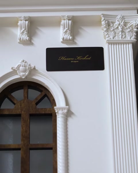 Detaliu de cornișă și placă decorativă lângă o fereastră cu ramă de lemn.