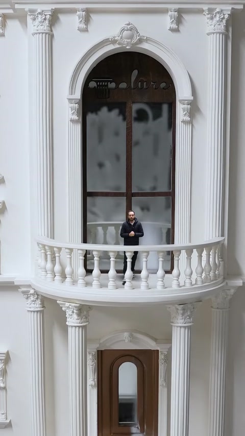 Balconul miniatural combină coloane, balustradă și ancadramentul unei ferestre arcuite.