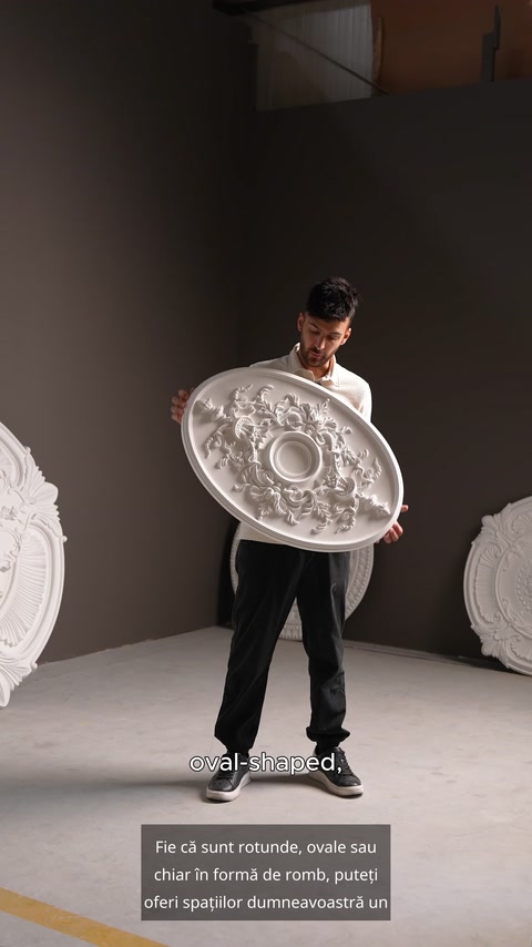 Prezentarea unei rozete ovale albe, ținută vertical în atelier.