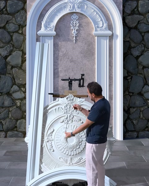 Bărbat fixează coloana lângă arcada decorativă de pe perete