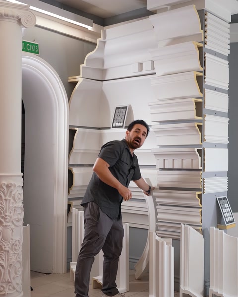 Bărbat îndoind un profil flexibil curbat lângă panoul expozițional