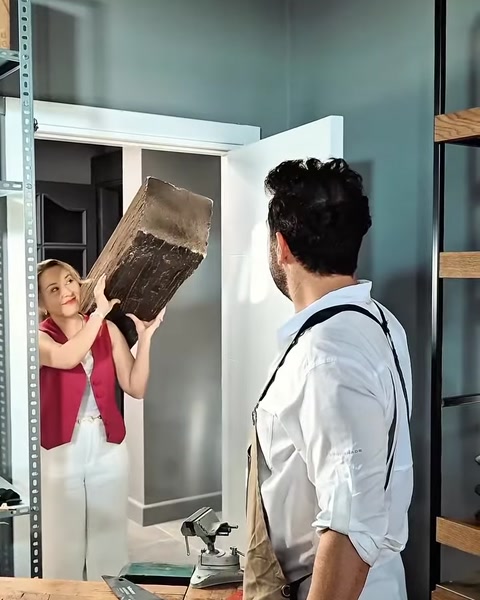 Bărbat preia grinda poliuretanică de la colegă, lângă intrarea atelierului.