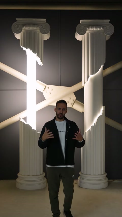 Prezentatorul stă între coloanele decorative cu inserții verticale iluminate.