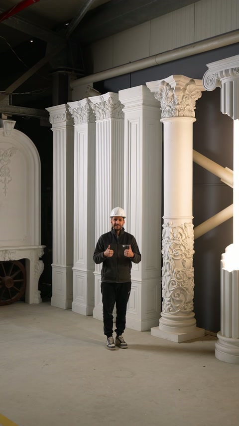 Coloana cilindrică sculptată este expusă vertical alături de prezentator.